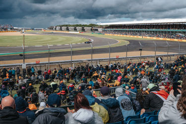 Un F1 en la curva de Chapel mientras los aficionados observan desde la tribuna