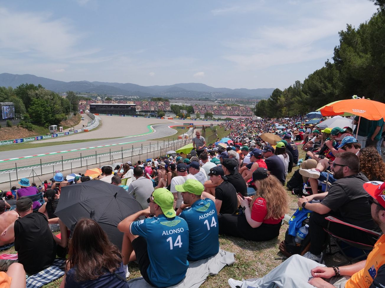 F1 fans sit on a hill overlooking the track at the Spanish GP