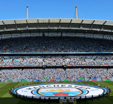 Gran bandera con el logo del Manchester City en el campo del Etihad Stadium antes del partido
