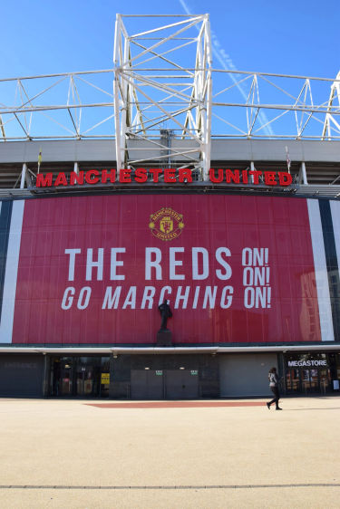 Estadio Old Trafford con el banner « The Reds Go Marching On » del Manchester United