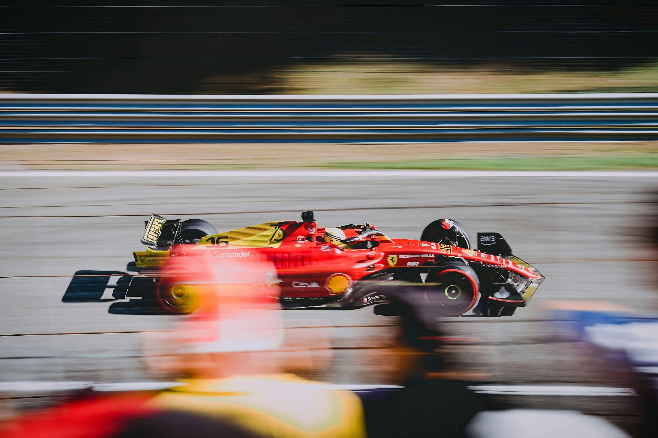A ferrari F1 car speeds past spectators