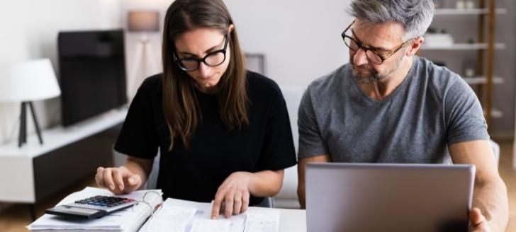 Woman looking at receipts and man using a laptop.