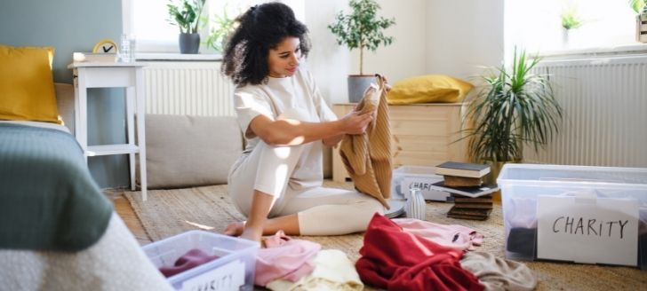 Woman cleaning out clothing and donating some to charity.