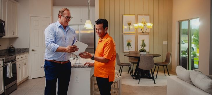 two people viewing a tablet standing in a kitchen