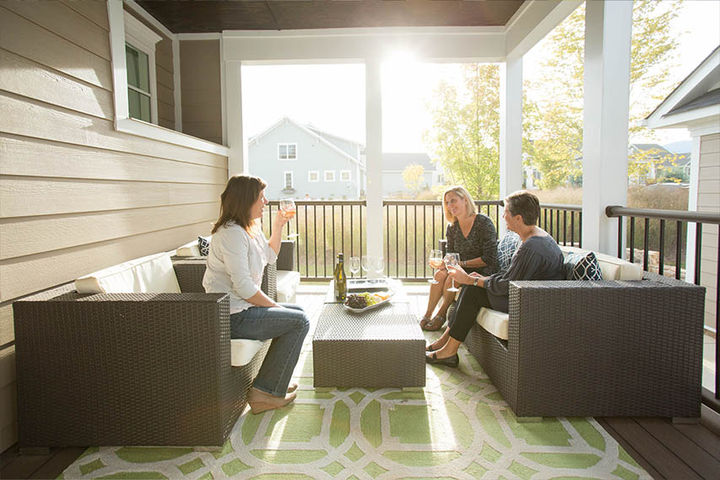 friends talking on rear covered porch of new construction home