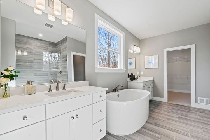 primary bath with separate dual cabinet vanities