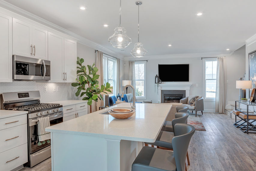 Kitchen with stool seating at island that flows into the family room