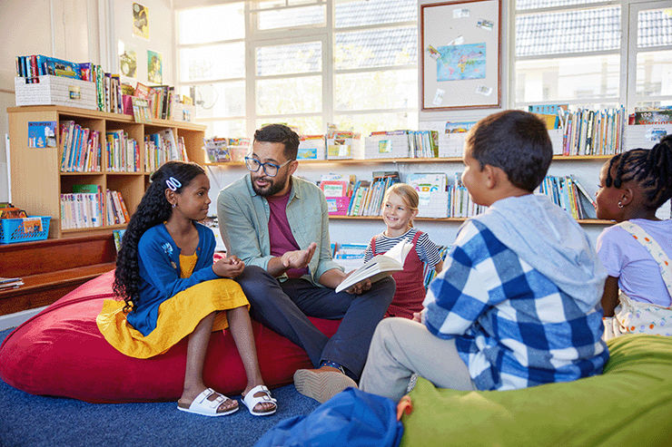 Adult male reading to a group of children in a library