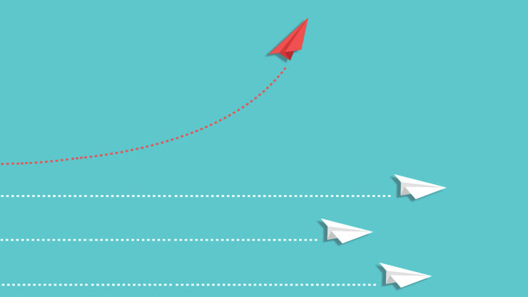Four paper aeroplanes on a light blue background. The top one is a different colour and is changing to go in a different direction to the other three. 