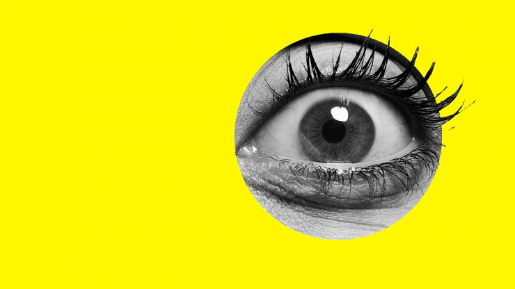 A large monochrome eye stares wildly out of a yellow background