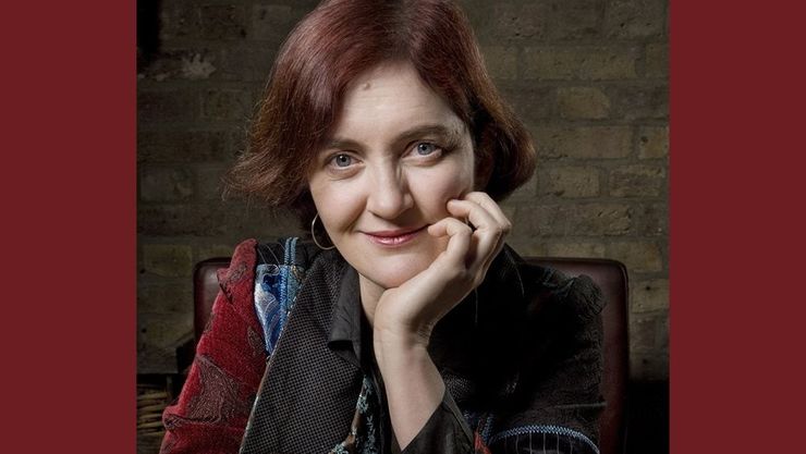 Photo of Emma smiling, with an exposed brick wall in the background