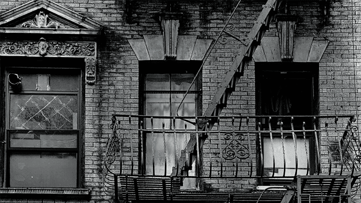 A black and white photograph of the outside of a New York City apartment building