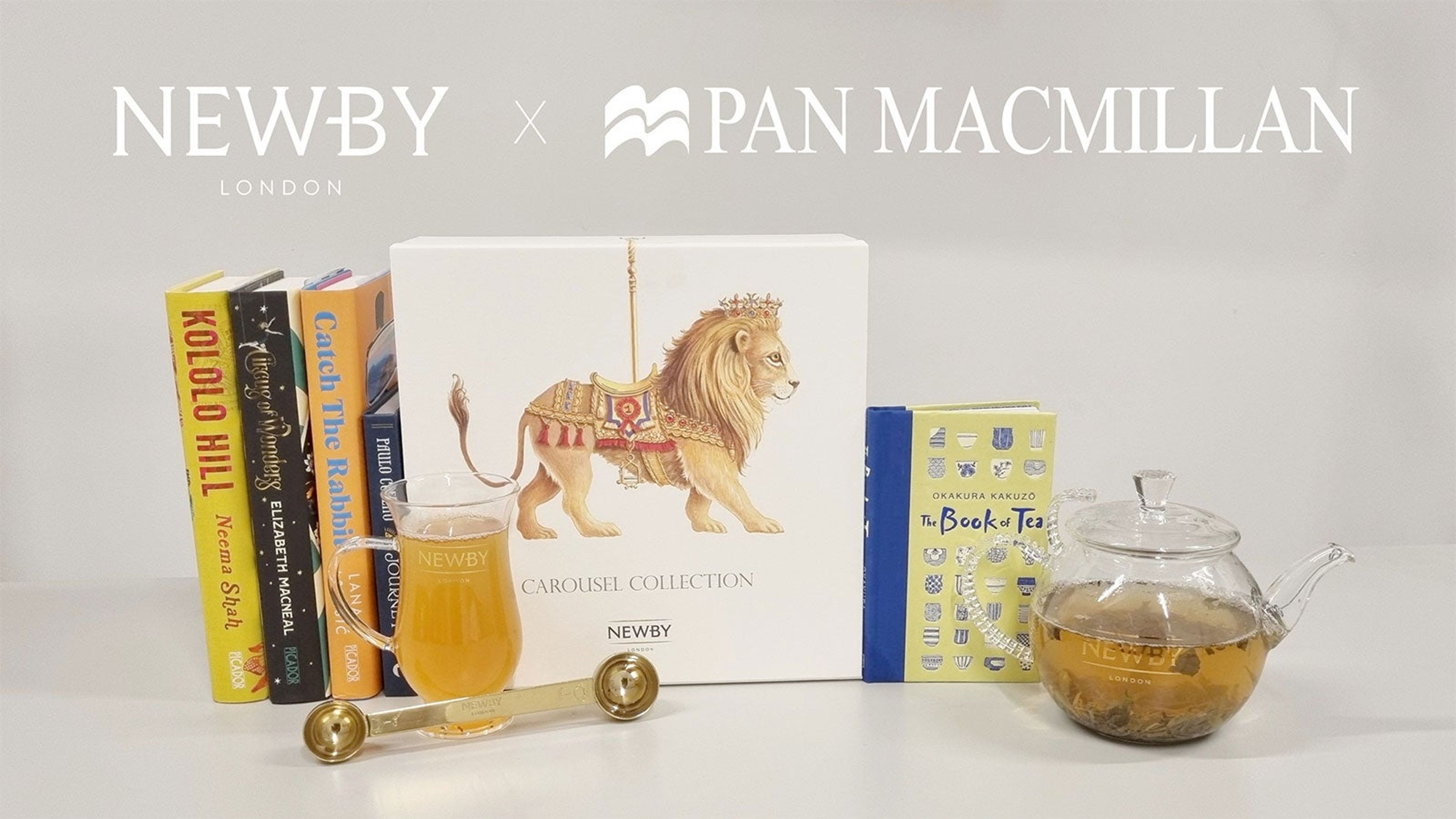 A collection of books, with a glass teapot and glass cup containing brewed loose leaf tea.