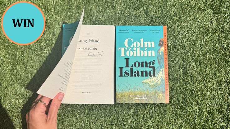Two copies of Long Island resting on grass. One is opened to display Colm Toibin's signature.