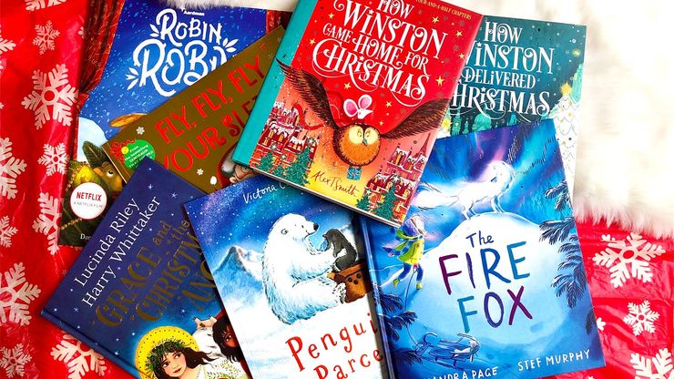 A bundle of children's Christmas books on a snowflake patterned table cloth.