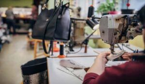Leather bag manufacturing process in India with skilled worker stitching handbags in an export-ready factory