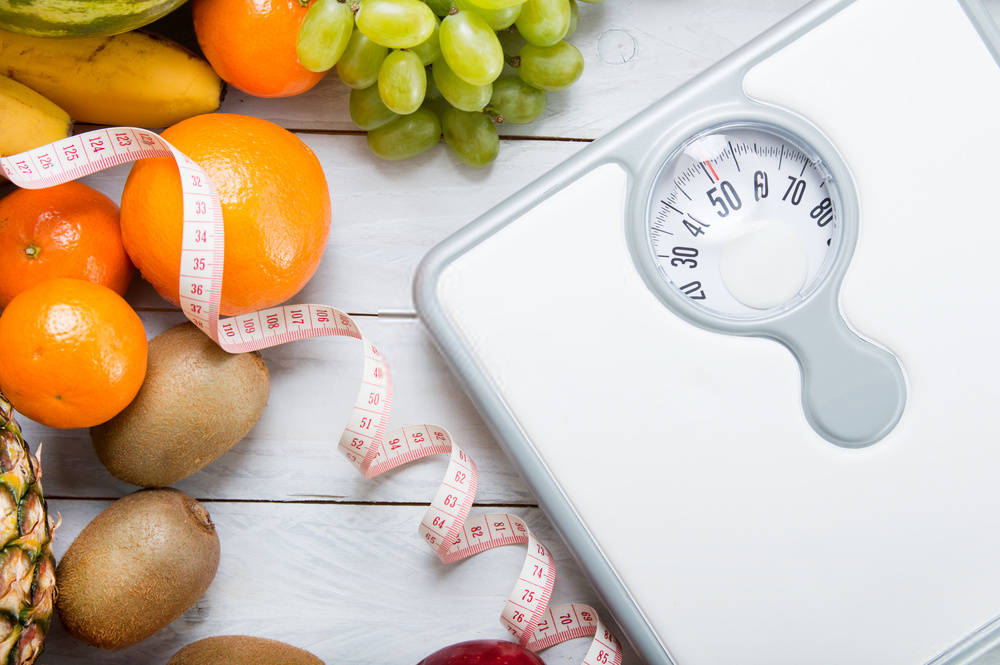 Stack of fruits, white weight scale and tailor meter
