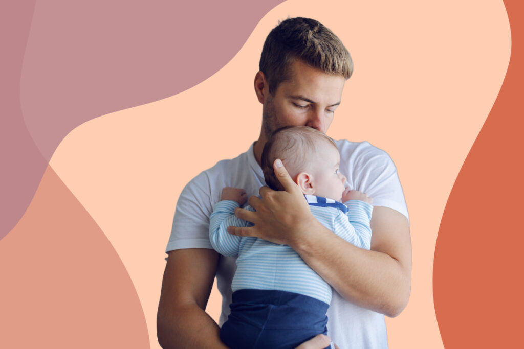 A father holding his small baby close and kissing them.