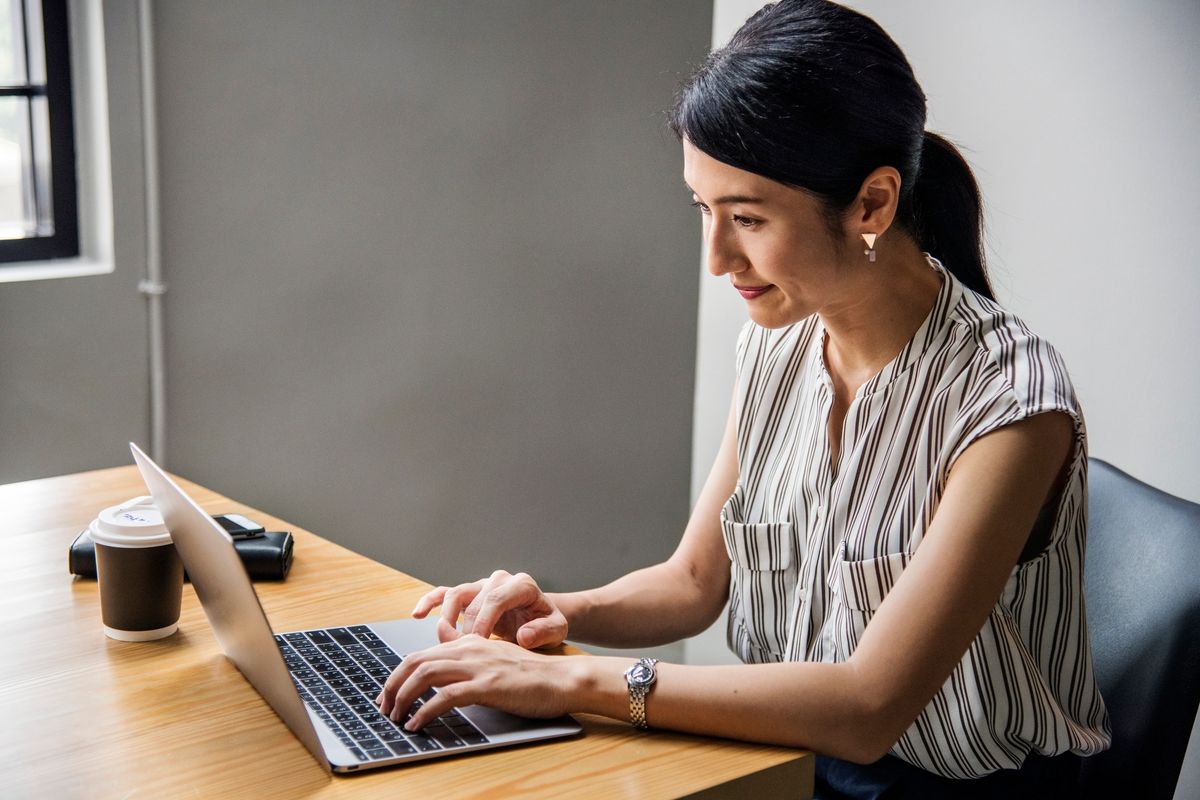 perempuan Asia membuka laptop dari tempat kerja online