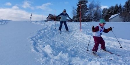 et barn og en voksen går på ski