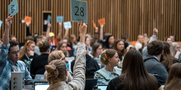 Studenter voterer med blå og oransje skilt. Foto. 