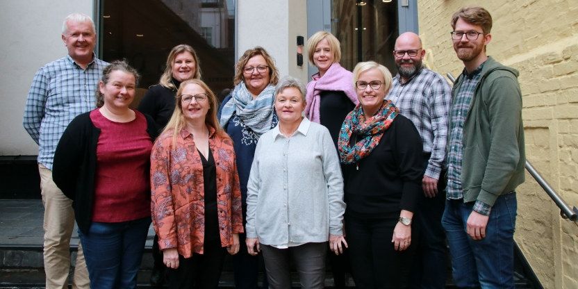 Valgkomiteens elleve medlemmer står oppstilt ute på en trapp for fotografen.