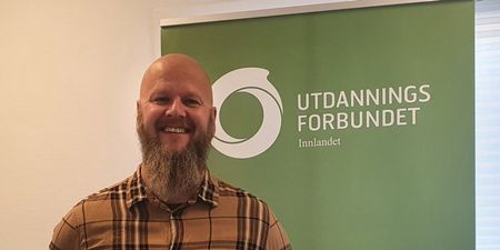 Bilde av en smilende fylkesleder Thore Johan Nærbøe foran en roll-up med logo og Utdanningsforbundet på