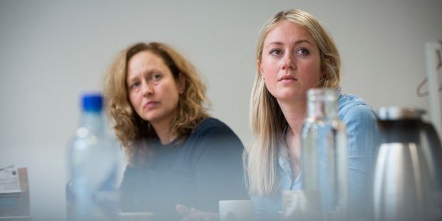 To personer som sitter rundt et bord og lytter. Foto. 