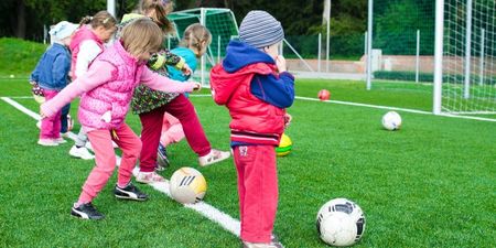 Illustrasjonsbilde av barn som spiller ball på en gressbane.