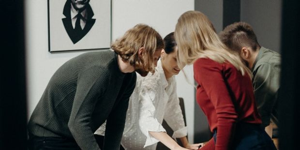 Illustrasjonsbilde av gruppe som står sammen og jobber med noe over et bord