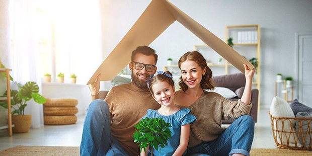 En far, mor og datter holder en papp-plate så den ligner taket på et hus