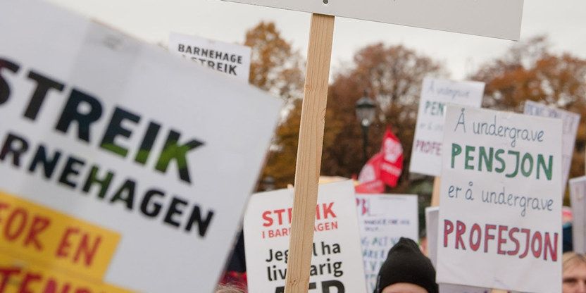 Nærbilde av flere streikeplakater som holdes av streikende. 