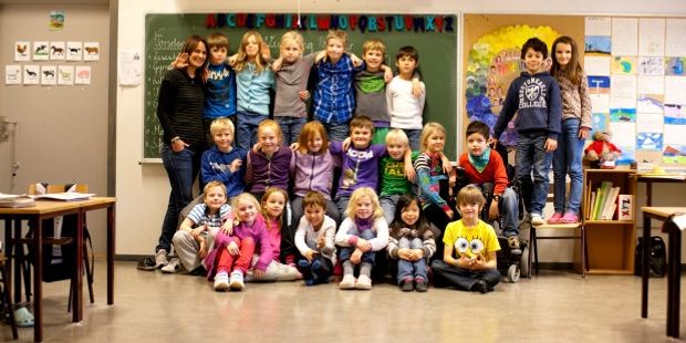Et klassebilde av 1 lærer og 22 elever. Foto.