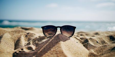 Bilde av en solbrille som ligger på en sandstrand