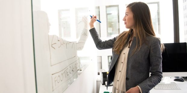 Kvinne som skriver på et whiteboard. Foto.