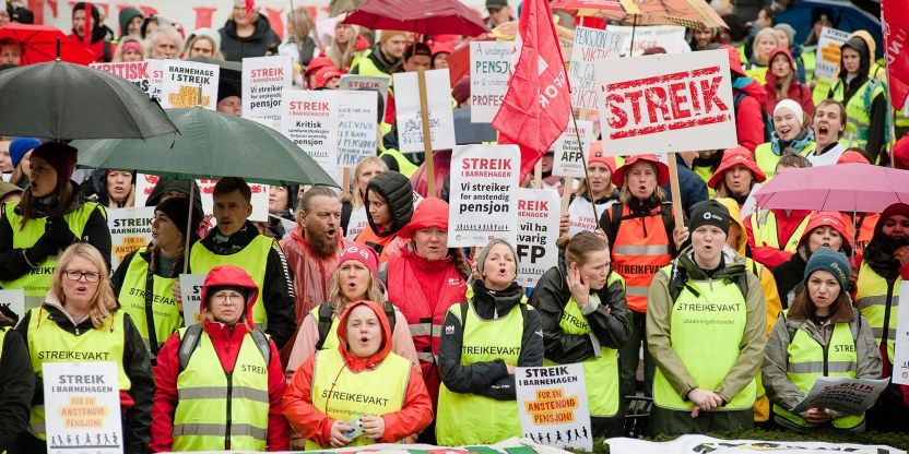Mange personer står foran Stortinget med streikeplakater og i streikevester og streike t-kjorter.