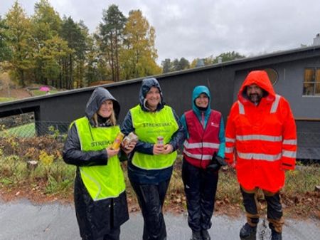 Vi ser 4 personer på streikevakt i regnvær.