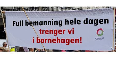 Foto av et 1. maibanner med teksten "Full bemanning hele dagen trenger vi i barnehagen"