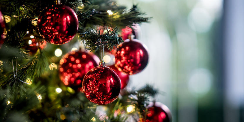 Røde julekuler på et grønt, kunstig juletre.
