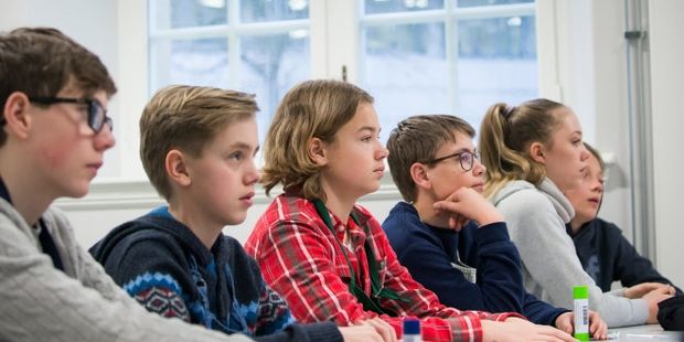 6 unge personer sitter på en rad og ser fremover. Foto.