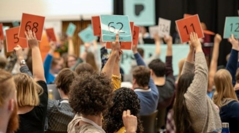 Mange mennesker som sitter i en sal med ryggen mot kamera. De fleste holder opp stemmeskilt. Bildet er tatt under landsmøtet til Pedagogstudentene i 2019. Foto: Chris-Håvard Berge/Oclin