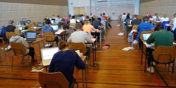Elever som har eksamen. Sitter ved pultene sine i et klasserom.