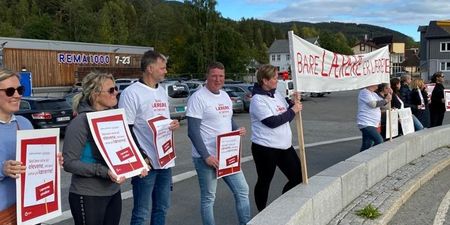 Bildet viser lærere med plakater stående ved siden av hverandre rundt rundkjøringen på Dokka. De holder oppe streikeplakater og banner