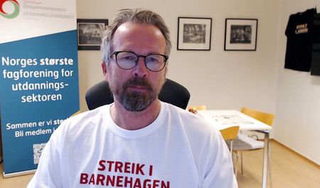 Fylkesleder Geir Røsvoll ikledd hvit tskjorte med påskriften "Streik i barnehagen". Bakgrunn kontormiljø, med rollup med teksten "Norges største fagforening for utdanningssektoren". FOTO