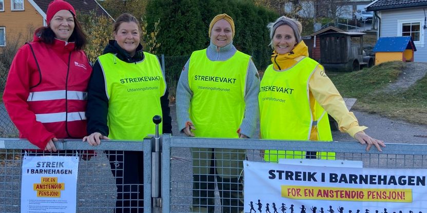 Bilde av 4 streikende i Strai barnehage. De har streikevester, banner og plakater.