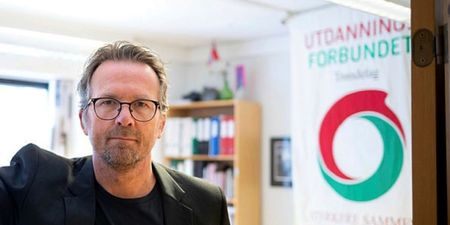 Hvit mann med briller i en døråpning med banner av UDF bak