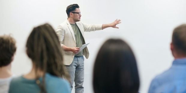 Lærer står foran studenter og forklarer. Illustrasjonsfoto