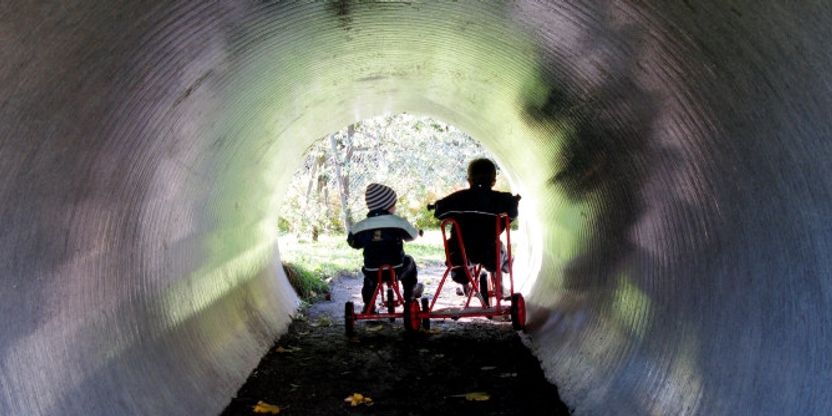 To barn på trehjulssykkel i tunnel. Foto