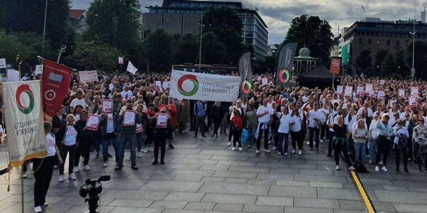 Mange streikende lærere i Bergen. De står ute, og har på seg hvite streike-t-skjorter. Utdanningsforbundets mange faner vaier i vinden. 