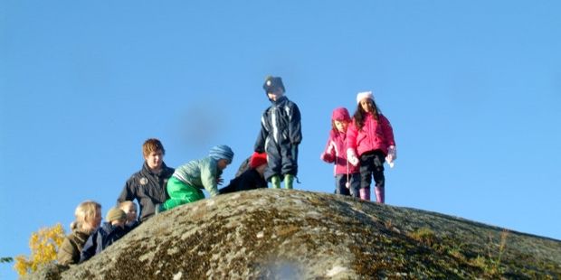 Barnehagebarn og barnehagelærere klatrer opp på en haug. Illustrasjonsfoto